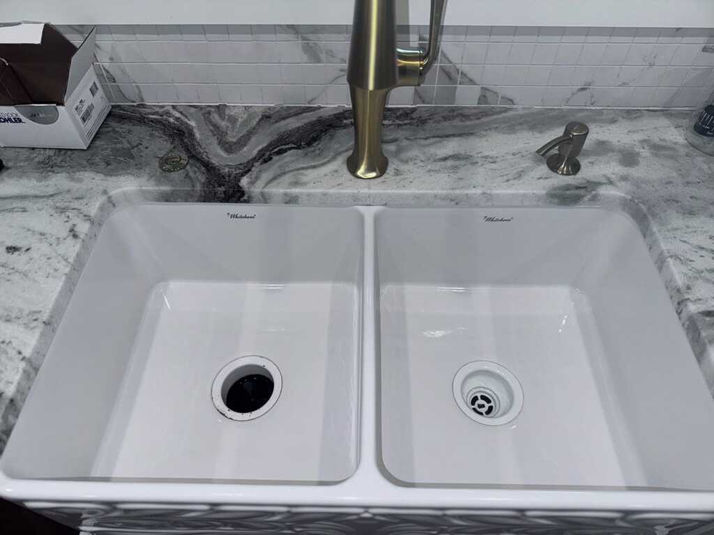 White farmhouse double-bowl sink with brushed gold faucet